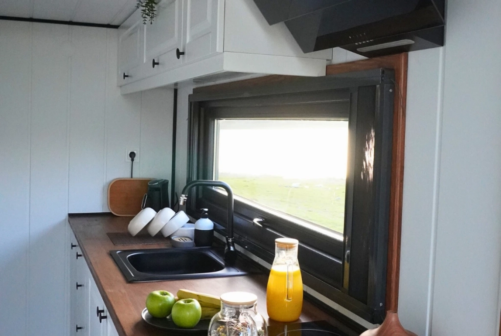 Modern tiny house mutfak tasarımı, ahşap tezgah, geniş pencere ve depolama alanlarıyla ferah yaşam alanı