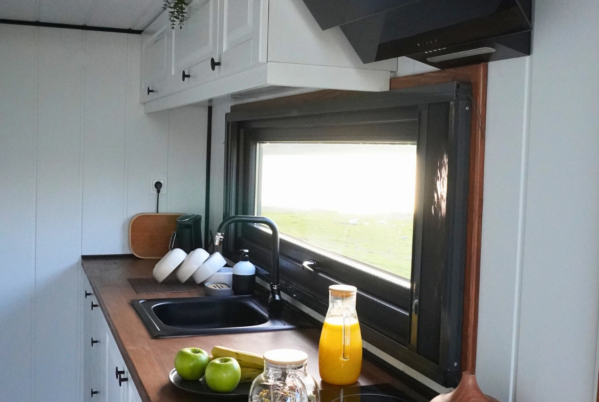 Modern tiny house mutfak tasarımı, ahşap tezgah, geniş pencere ve depolama alanlarıyla ferah yaşam alanı